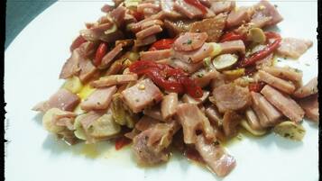 Un plato de carne en rodajas con verduras y un chorrito de aceite.