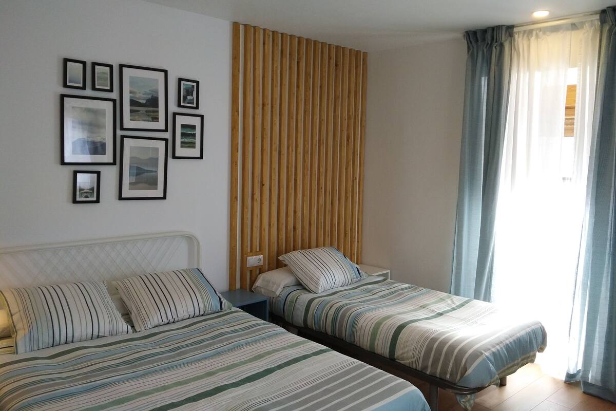 Una habitación con dos camas, un muro de listones de madera y cuadros en la pared.
