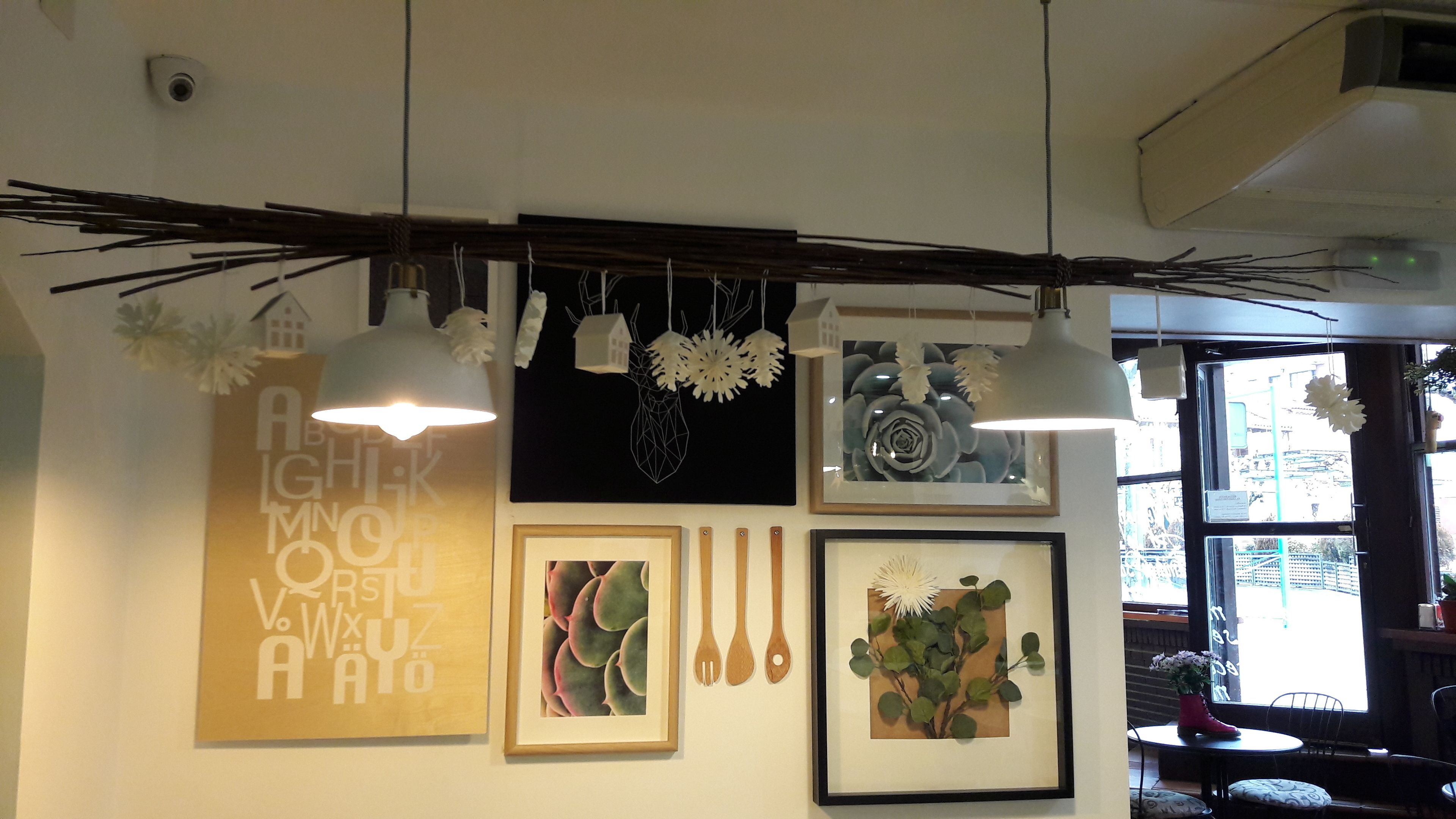 Een kamer met een plafondlamp, een beveiligingscamera aan de muur en een raam met uitzicht op de straat.