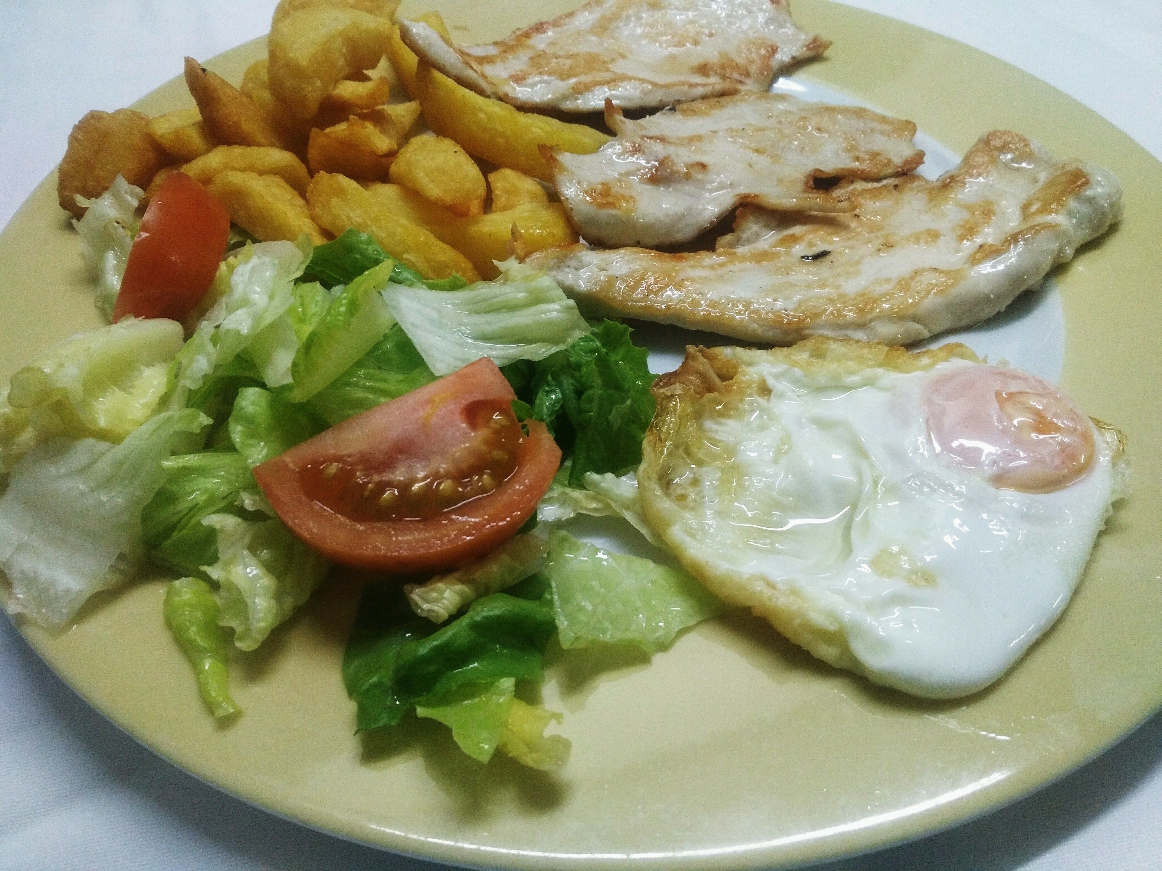 A plate with fried eggs, French fries, and a salad.