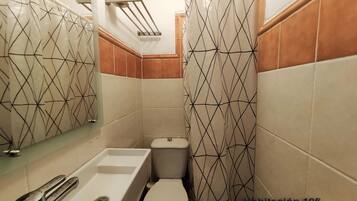 Un baño con bañera, inodoro y cortina de ducha de diseño geométrico.