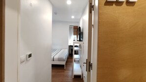 Ein Korridor führt zu einem Schlafzimmer mit einem Bett, einem Schreibtisch mit Computer und einem Badezimmer. Die Zimmernummer ist 105.