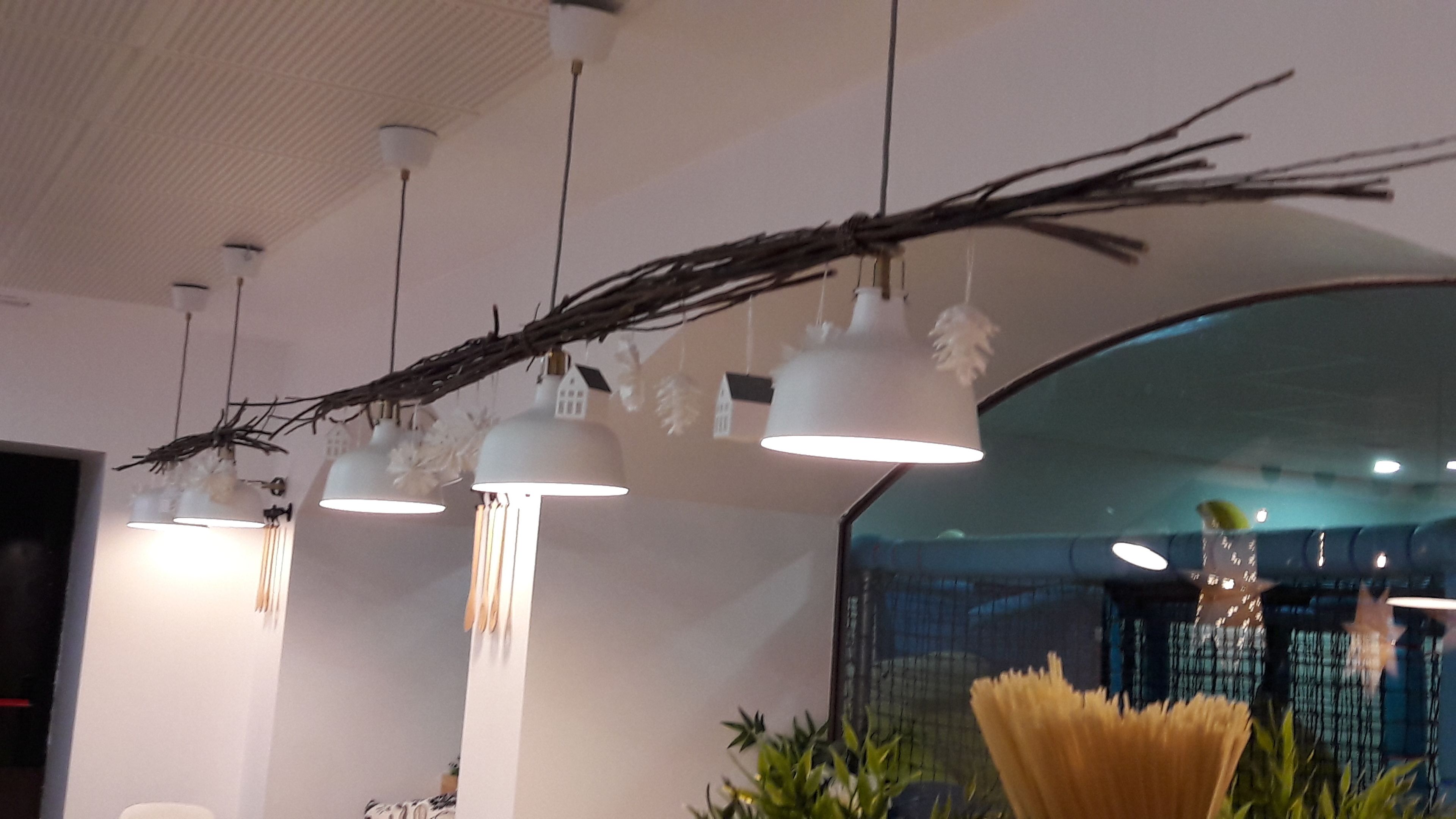 Un interior moderno con lámparas colgantes, una rama decorativa y vistas de la ciudad a través de un ventanal grande.