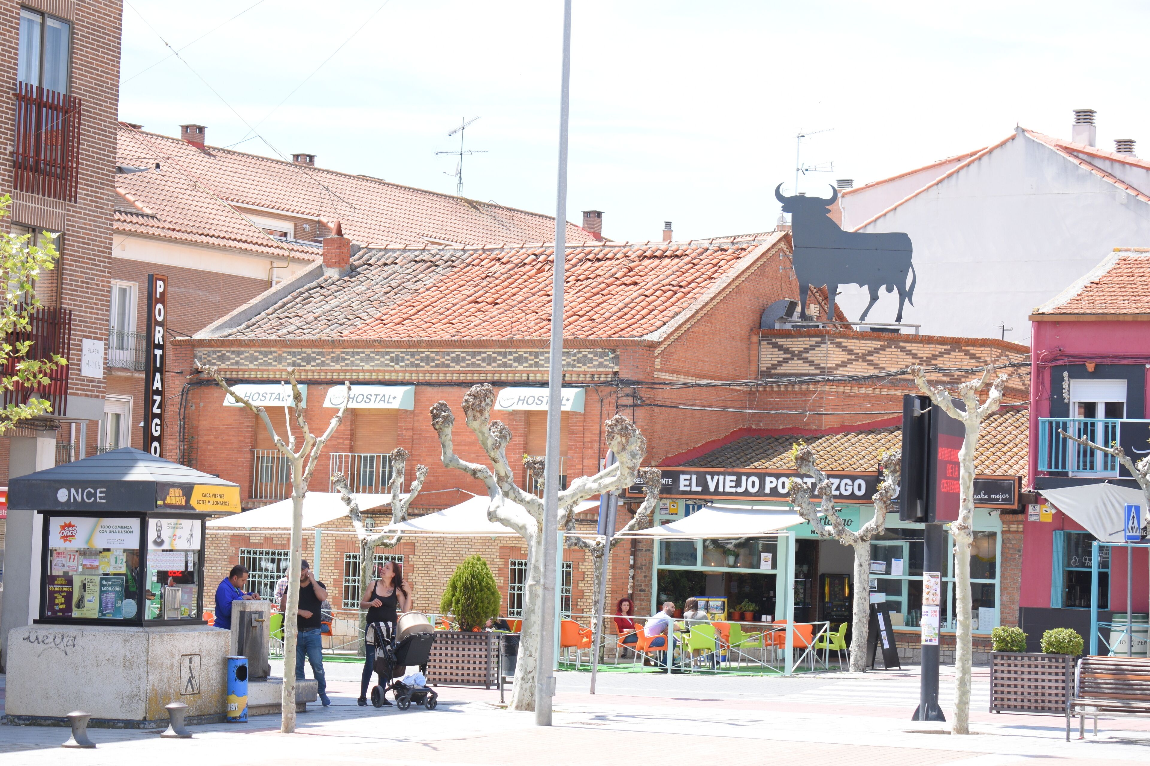 Straatbeeld met een restaurant genaamd "El Viejo Postezgo" en een stierbeeld op een gebouw.