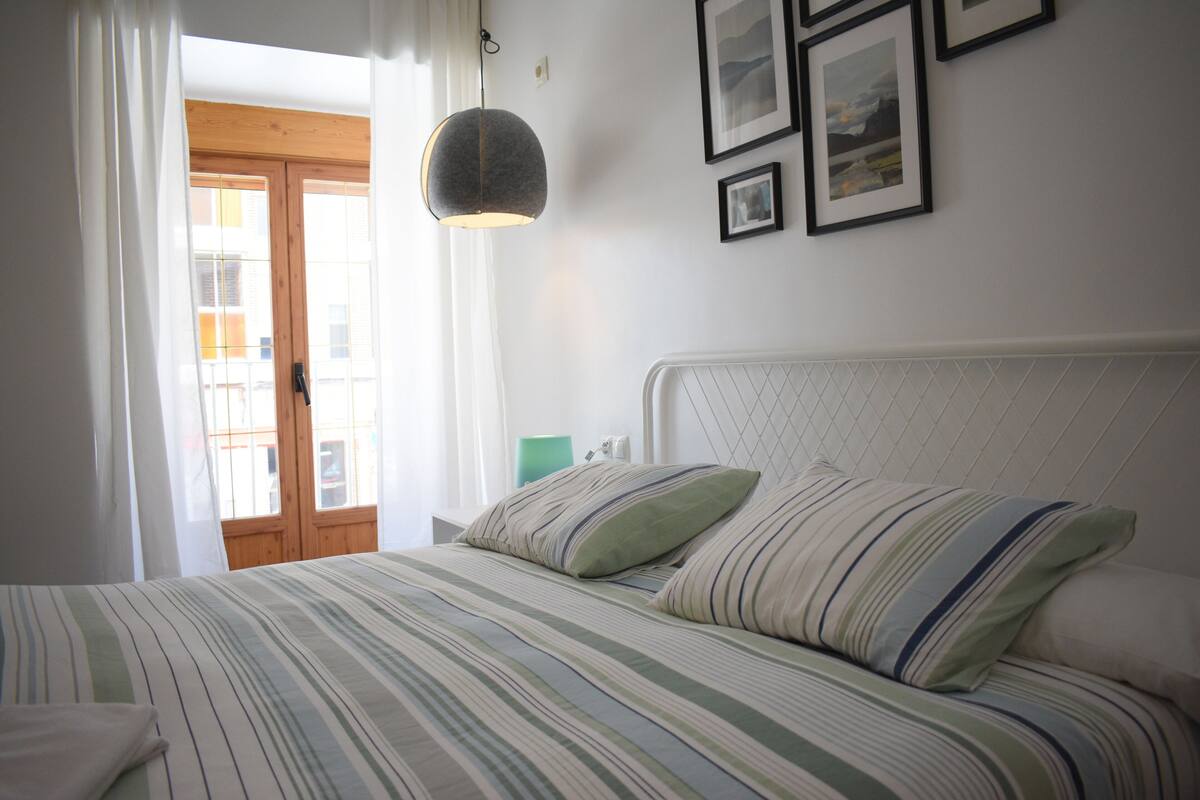 Un dormitorio con cama, lámpara colgante y cuadros en la pared.