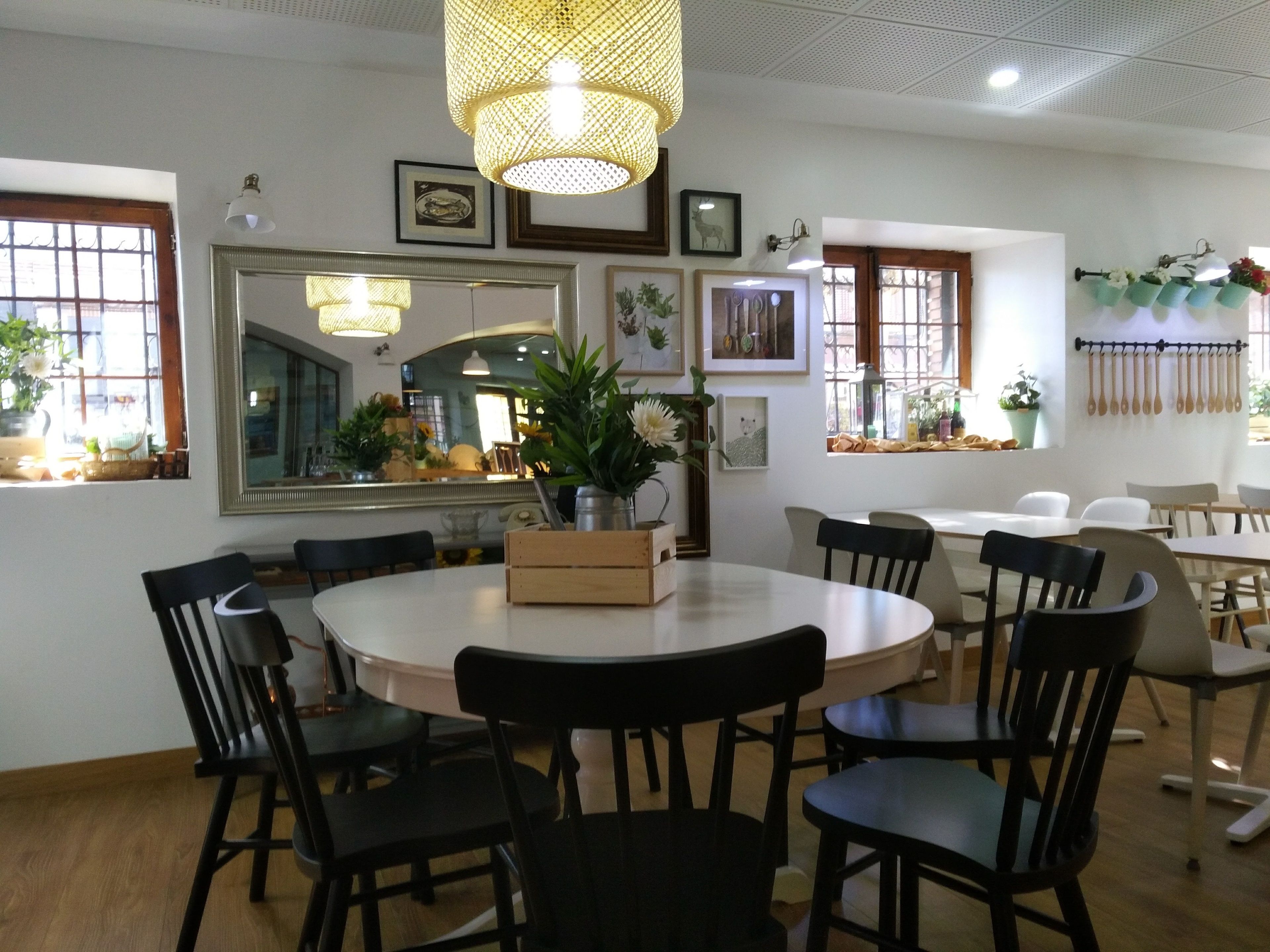 Un comedor con una mesa redonda, sillas negras, una lámpara colgante y cuadros en las paredes.