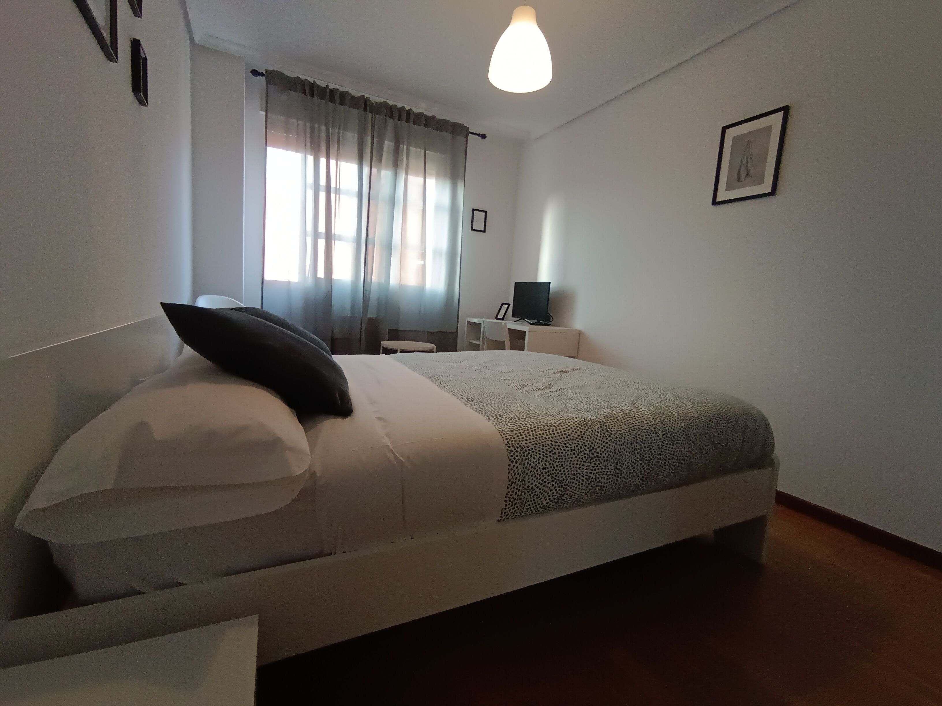 A neatly arranged bedroom with a bed, a desk, and a chair.