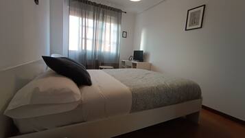 A neatly arranged bedroom with a bed, a desk, and a chair.