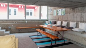 Eine moderne Küche mit einer Betonwand, Holzsitzen, einem Streifenmuster-Teppich und Blick auf ein rotes Gebäude.