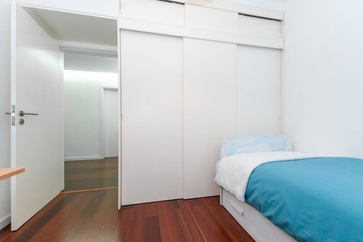 Un dormitorio con cama, armario y suelo de madera.