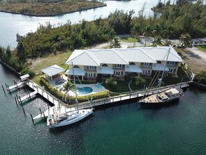 Une grande maison à plusieurs étages, dotée d’une piscine et d’un quai où sont amarrés des bateaux.