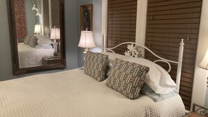 A neatly made bed with patterned pillows, a bedside lamp, and a mirror reflecting part of the room. - Pegasus Lair Upper Floor Apt.NoPetFee, NoChores.Short Walk to Satellite Venue! (Memphis)