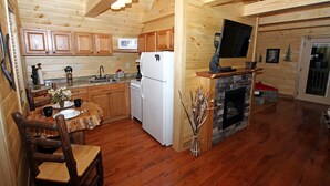 A wooden cabin interior with a kitchen, dining area, and fireplace. - Gatlinburg Cabin Free Tickets, Heart Whirlpool, Hot Tub, King Bed, Fast Internet (Gatlinburg)