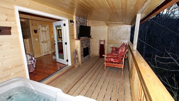A wooden deck with a hot tub, a fireplace, and a sofa. - Gatlinburg Cabin Free Tickets, Heart Whirlpool, Hot Tub, King Bed, Fast Internet (Gatlinburg)
