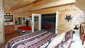 A wooden cabin bedroom with a large bed, a red bathtub, a wooden dresser, and a mirror. - Gatlinburg Cabin Free Tickets, Heart Whirlpool, Hot Tub, King Bed, Fast Internet (Gatlinburg)