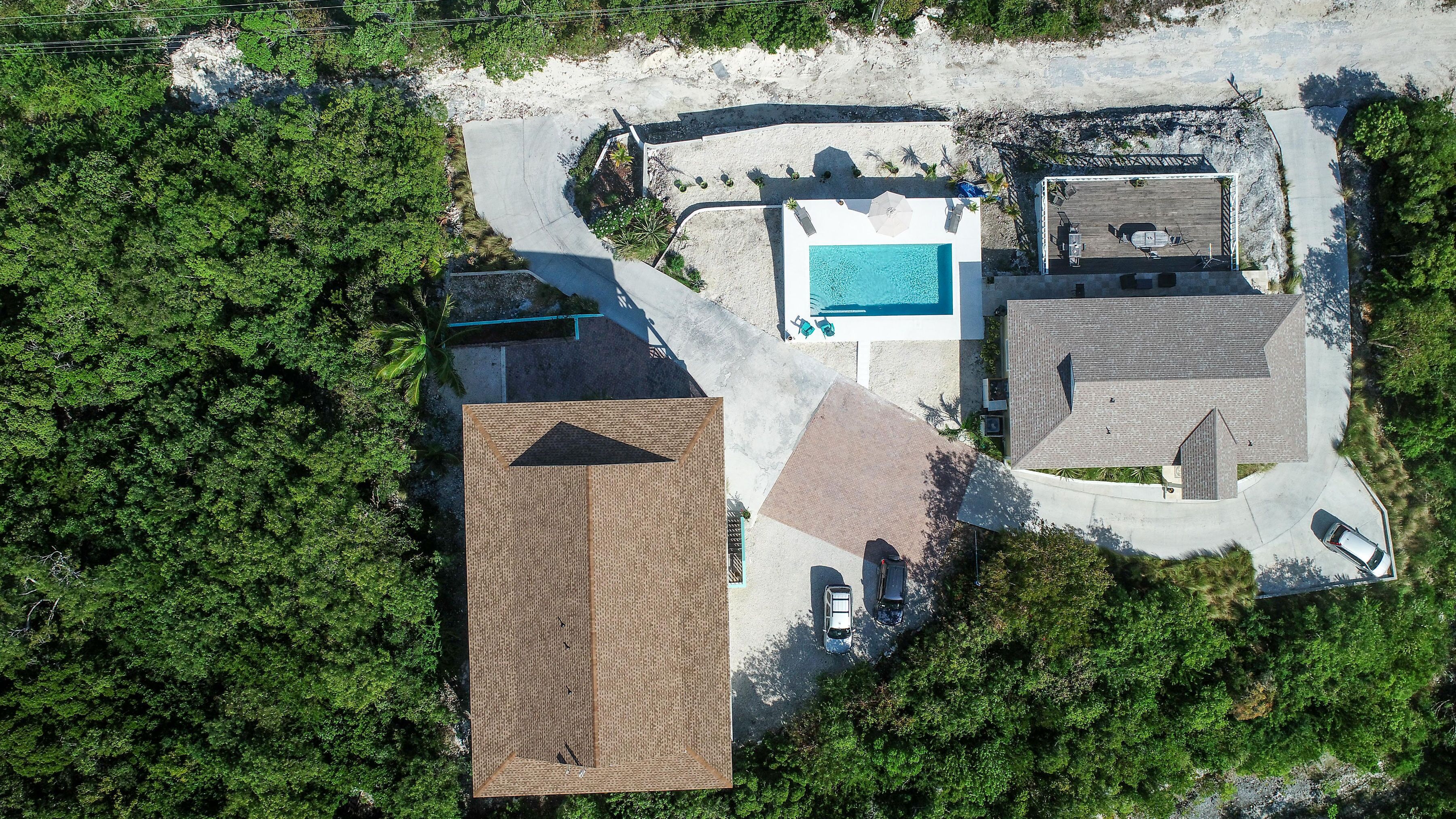 An aerial view of a property with a swimming pool, a covered patio, and a large brick building.