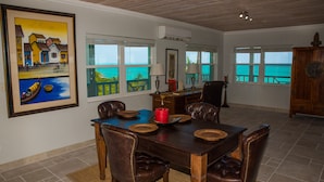 A dining area with a wooden table, leather chairs, and a painting of a coastal scene.