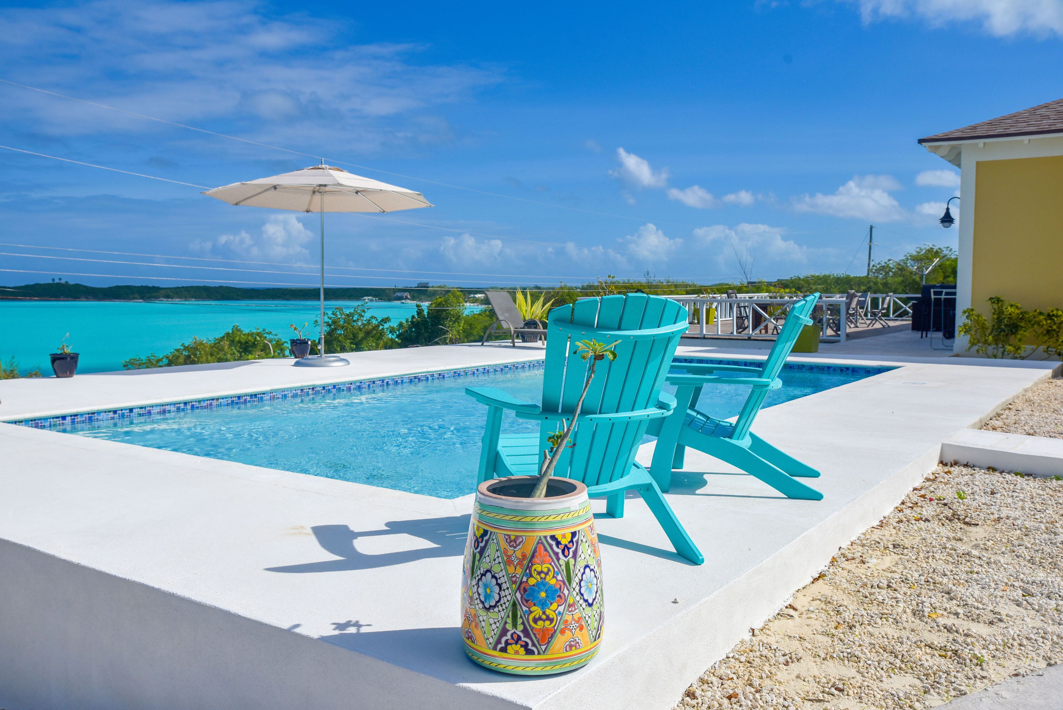 A pool area with turquoise chairs and a colorful planter.
