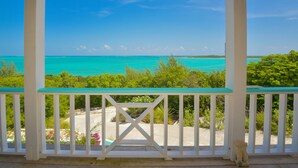 A balcony with a view of turquoise waters and greenery.