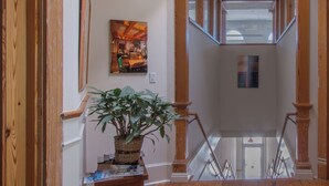 A staircase with wooden railings, a potted plant, and a framed picture on the wall.