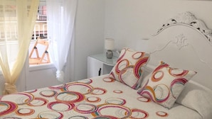 Un dormitorio con cama, almohadas, mesita de noche, lámpara y un adorno en la pared.