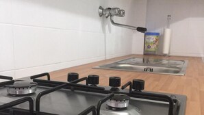 Una cocina con estufa a gas, un fregadero y un armario con pomos.