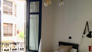 A room with two beds, a window with a view of buildings, a radiator, and a patterned rug. - Very central apartment in Bilbao a few meters from Gran Vía,  E-BI-752. (Bilbao)