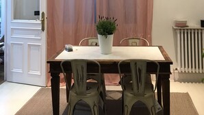 A dining area with a table, chairs, a potted plant, a clock, and a window with curtains. - Very central apartment in Bilbao a few meters from Gran Vía,  E-BI-752. (Bilbao)
