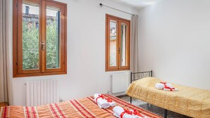 Une chambre avec deux lits, une fenêtre et un radiateur.