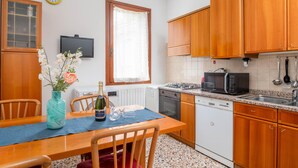 Une cuisine avec des meubles de rangement en bois, un four à micro-ondes, un évier et une table à manger avec des chaises.