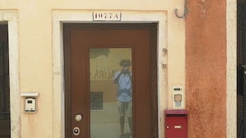 Entrada de un edificio con un letrero que dice "RUGA BELLA" y una puerta marcada con el número "1077A".