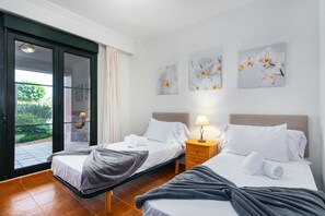Una habitación de hotel con dos camas, una puerta corrediza al exterior y obras de arte en las paredes.