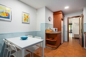 Una cocina con una mesa blanca, salpicadero de azulejos azules y un microondas en la encimera.
