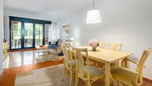 A dining area with a table and chairs, a hanging light fixture, and a view through a glass door to an outdoor balcony. - El Rincon del Golf I - Isla Canela Golf GRHI6P06 (Isla Canela)