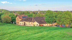 A rural building with a sloped roof, surrounded by green fields and trees. - Amazing apartment in Simpelveld (Simpelveld)