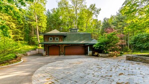 A house with a brick exterior, a green roof, and a driveway leading to a garage.