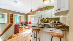 A modern kitchen with white cabinets, a granite countertop, and a central island with stools.