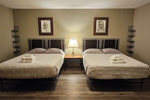 Una habitación de hotel con dos camas, una mesita de noche con lámpara y cuadros en las paredes.