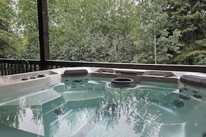 A hot tub with a view of a forested area.