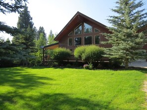 A modern house with a sloped roof, large windows, and a well-maintained lawn.