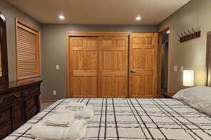 A bedroom with a bed, a dresser, a double door closet, and a wall-mounted lamp.