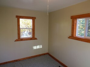 A room with two windows, wooden trim, and a carpeted floor.