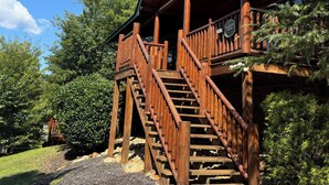 Une cabane en bois avec une véranda et un escalier menant à une terrasse.