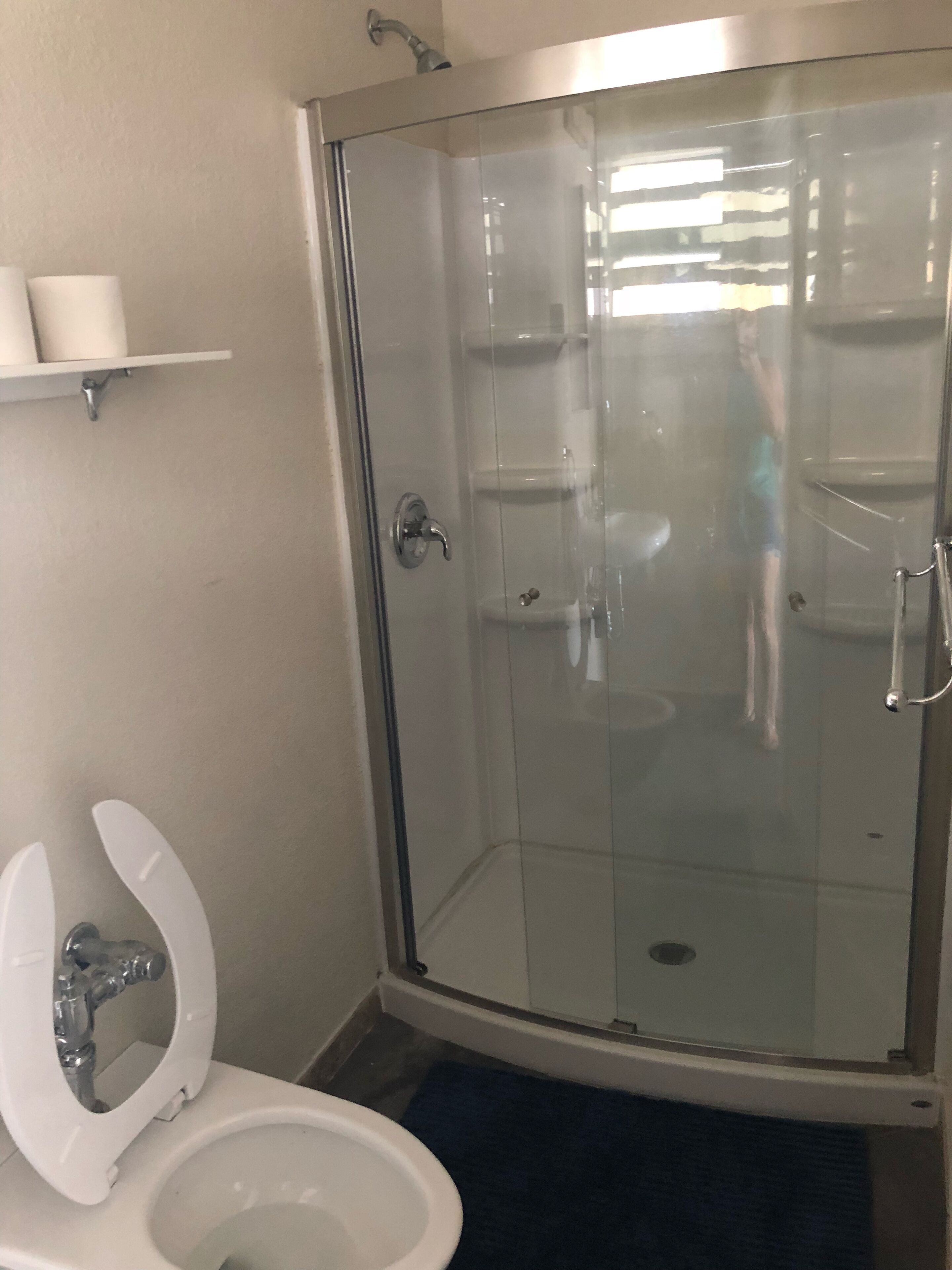 Un baño con ducha de vidrio, inodoro y lavamanos.