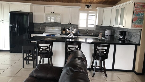 A modern kitchen with white cabinets, a black refrigerator, and a central island with bar stools. - "Canal-Front Paradise in Big Pine Key-Relax &Explore the keys" (Big Pine Key)