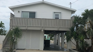 A two-story house with a covered porch and a small staircase leading to an upper level. - "Canal-Front Paradise in Big Pine Key-Relax &Explore the keys" (Big Pine Key)