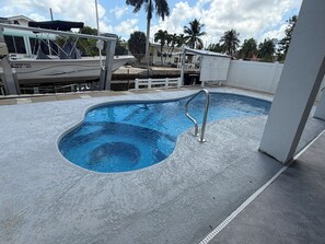 A swimming pool with a metal ladder, surrounded by a concrete deck and a white fence. - "Canal-Front Paradise in Big Pine Key-Relax &Explore the keys" (Big Pine Key)