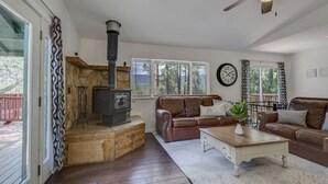 Un salon chaleureux avec une cheminée en pierre, des canapés en cuir, une table basse en bois et un ventilateur de plafond.