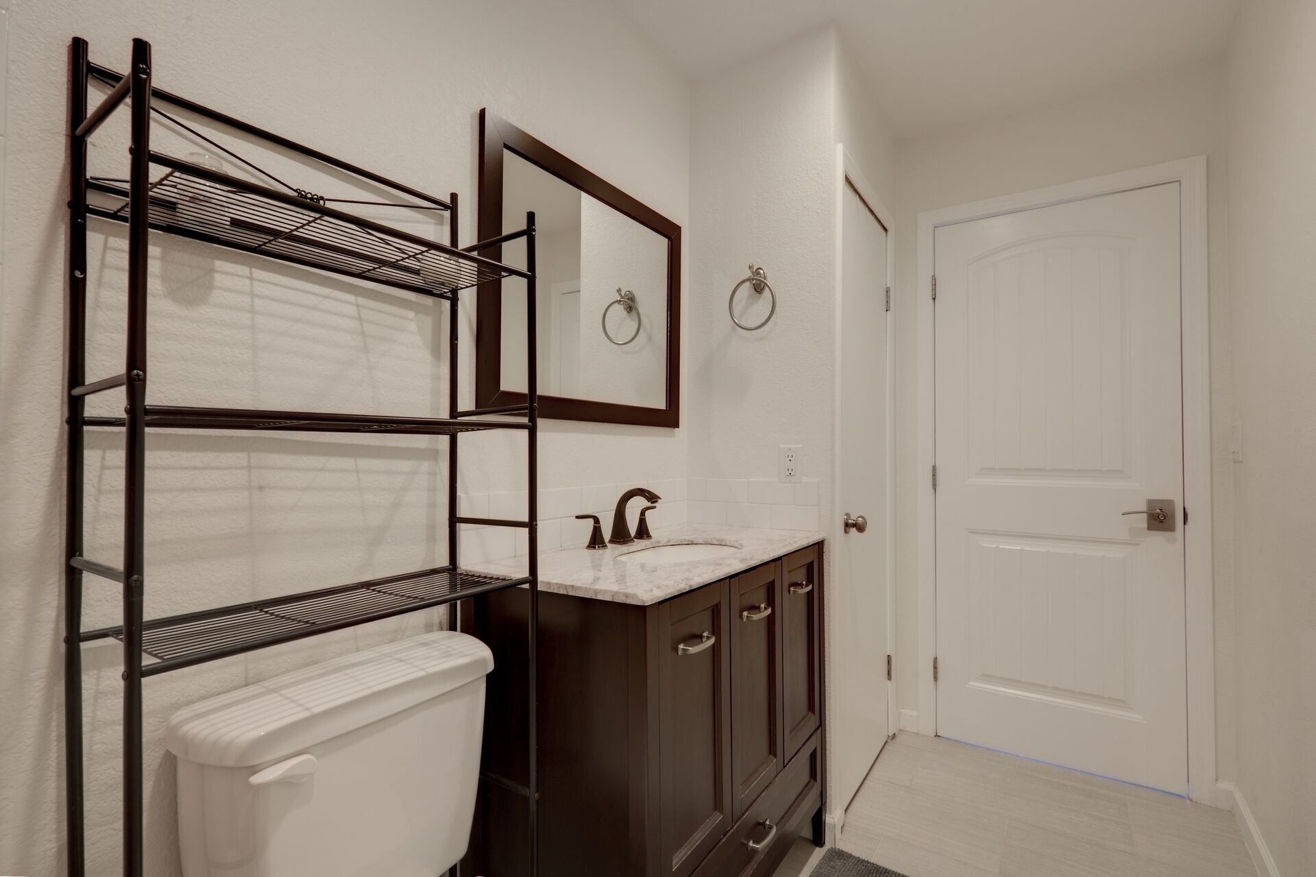 A bathroom with a toilet, a sink, a mirror, and a door.