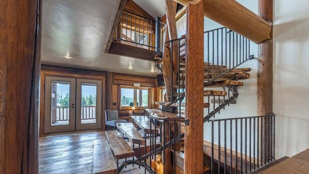 Ein geräumiges Zimmer mit einer Holztreppe und einem Balkon mit Sitzgelegenheit im Freien.
